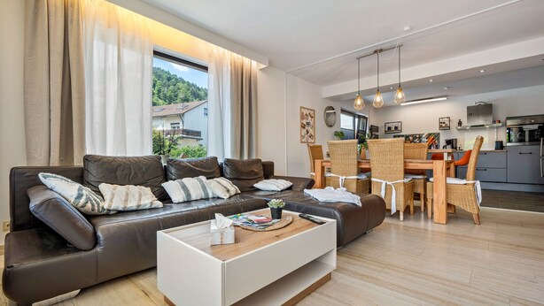 Una sala de estar moderna con un sofá, una mesa de centro y una zona de comedor.