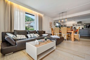 A modern living room with a sofa, coffee table, and dining area.