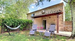 Un edificio rustico in pietra con un portico coperto, due sedie e un’amaca.