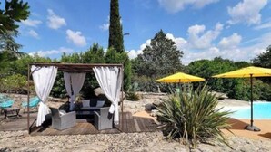 A covered outdoor seating area with a pool in the background. - La Béalière - A 4-star haven of peace in the heart of Ardèche (Labeaume)