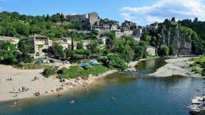 A riverside town with buildings, a beach, and people swimming. - La Béalière - A 4-star haven of peace in the heart of Ardèche (Labeaume)