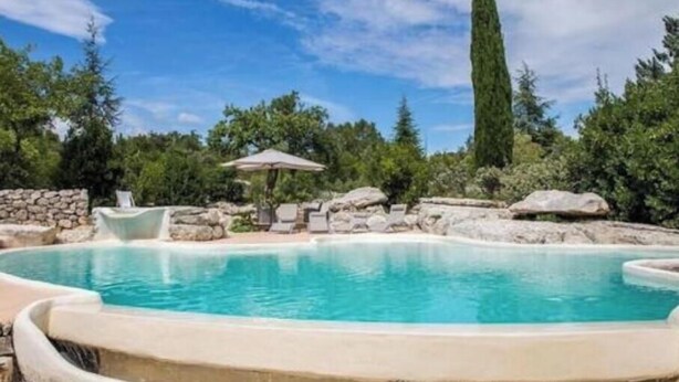 A swimming pool with a stone wall, lounge chairs, and a tall tree. - La Béalière - A 4-star haven of peace in the heart of Ardèche (Labeaume)