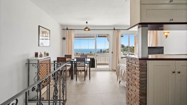 A spacious living area with a balcony, a dining table, and a kitchen area. - 2 Bed Panoramic Sea Views RDR543 (Benalmádena)