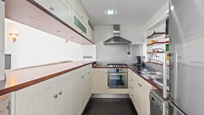 A narrow kitchen with white cabinets, a stove, oven, and a dishwasher. - 2 Bed Panoramic Sea Views RDR543 (Benalmádena)