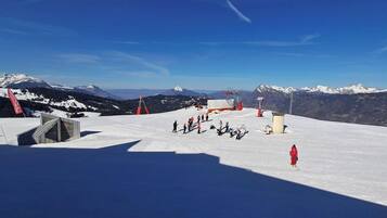 Een piste met skiërs, een skilift en een berg op de achtergrond.