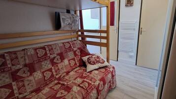 Een kamer met een houten stapelbed, een gestreept sofa, een decoratief kussen, en een schuifdeur.