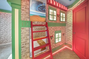 A room with a brick wall, a red door, a ladder, and a window with shutters. - 5BR house sleeps 14 near Disney area (Clermont)