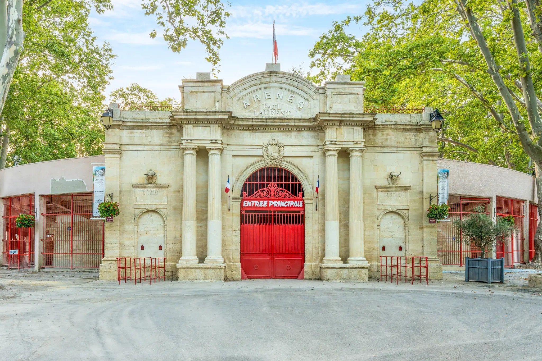 Een historisch gebouw met een opvallende ingang, voorzien van een rode poort waarop 'ENTREE PRINCIPALE' staat.