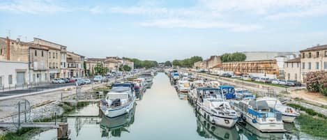 Un canal bordeado de barcos y edificios, con un puente y cielo despejado.
