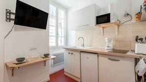 A modern kitchen with a flat-screen TV, white cabinets, a wooden countertop, and a window. - Holiday Home 'Studio Cocooning Beaucaire C3' with Wi-Fi (Beaucaire)