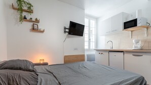 A bedroom with a bed, a TV mounted on the wall, and a kitchenette with a microwave and coffee maker. - Holiday Home 'Studio Cocooning Beaucaire C3' with Wi-Fi (Beaucaire)