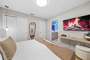 Ein modernes Schlafzimmer mit einem großen Bett, einem Fernseher und einem Spiegel.