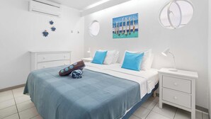 Une chambre à coucher comprenant un lit, des tables de chevet, un climatiseur fixé au mur et un tableau.