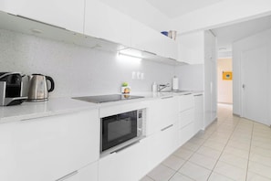 A modern kitchen with white cabinetry, a built-in oven, a kettle, and a microwave. - Belair Caribbean Sea with spectacular ocean views and house reef directly in front of the studio (Kralendijk)