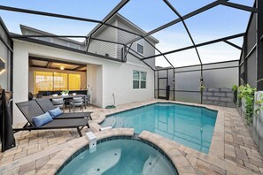 Una piscina con jacuzzi, tumbonas y un patio cubierto.