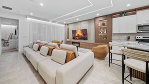 Uma sala moderna com sofá, televisão e área de cozinha.