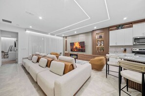 Ein modernes Wohnzimmer mit Sofa, Fernseher und Küchenzeile.