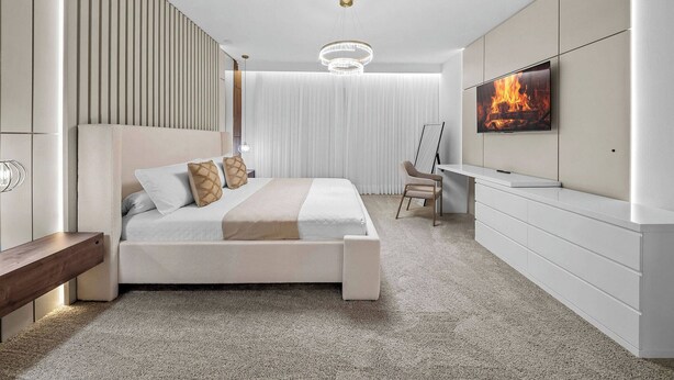 Quarto moderno com cama, mesa de cabeceira, televisão e área de trabalho.