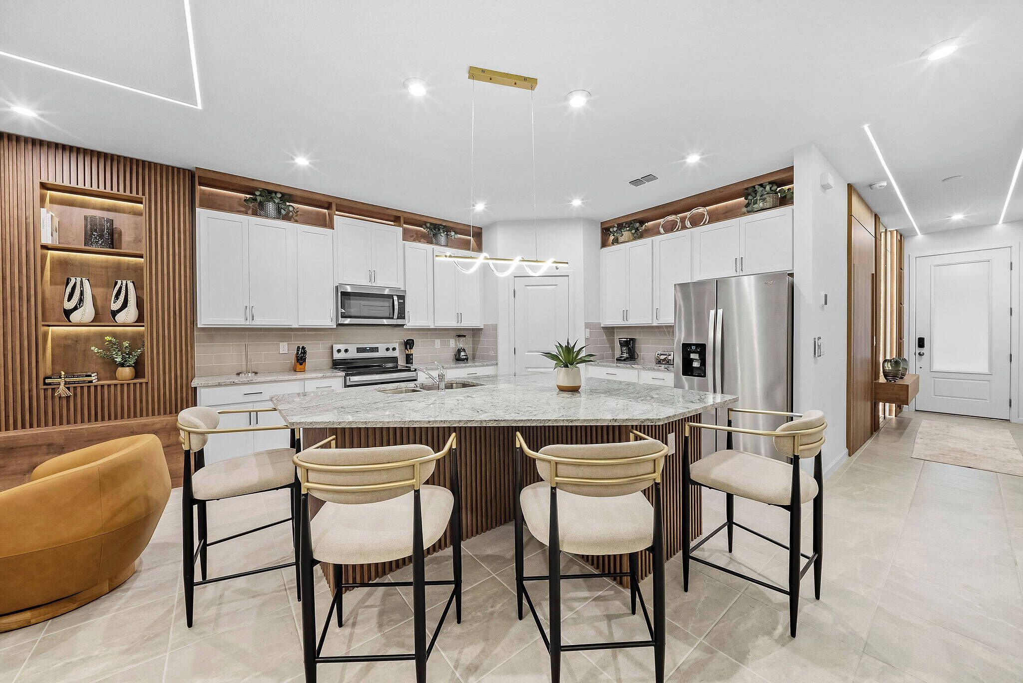 A modern kitchen with a central island, bar stools, and built-in appliances.
