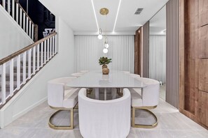 Ein stilvoller Essbereich mit einem weißen Tisch, passenden Stühlen und einer Treppe mit Holzgeländern.
