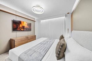 Un dormitorio moderno con cama, cómoda de madera, televisor de pantalla plana y lámpara en el techo.