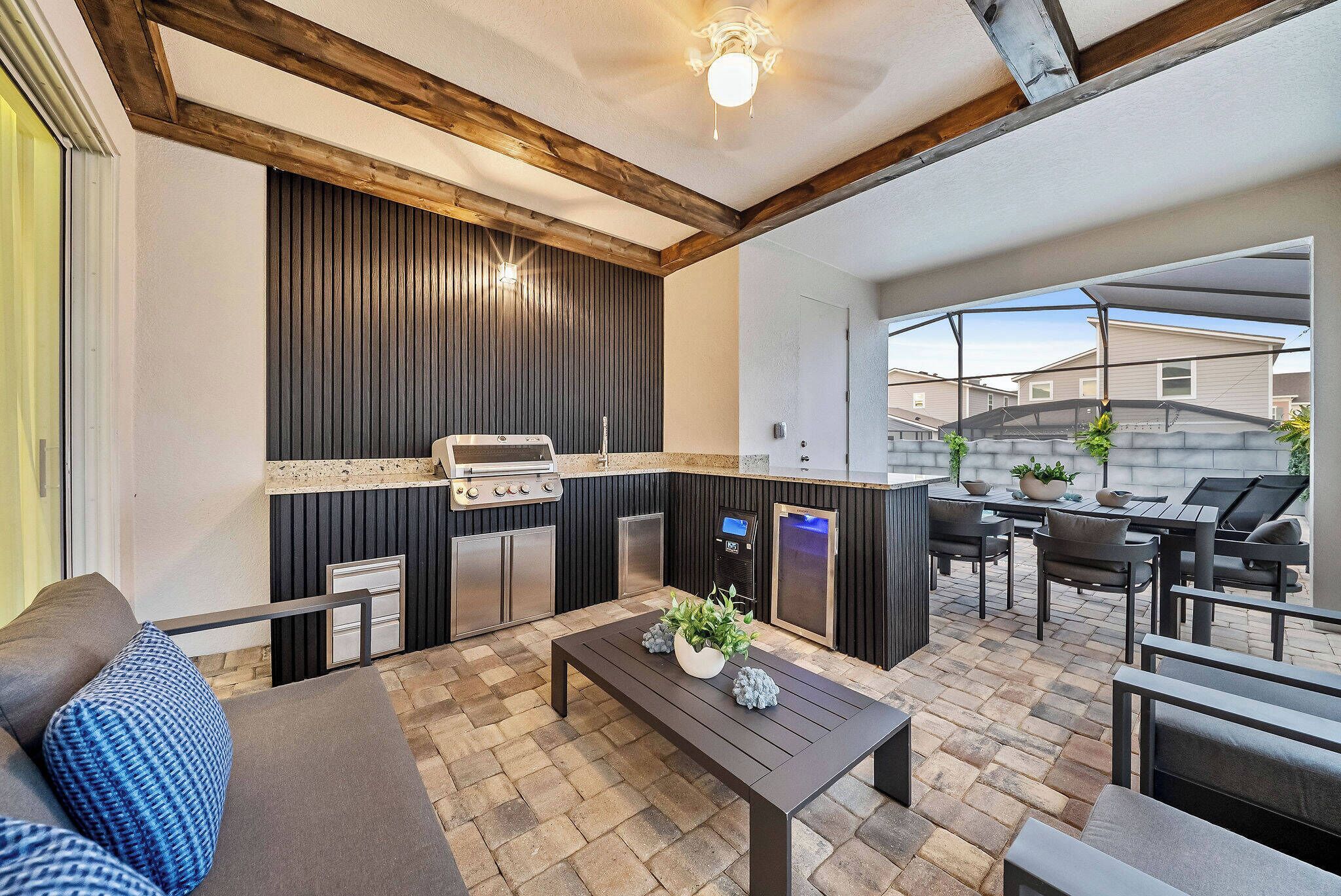 An outdoor patio with a grill, seating, and a stone floor.