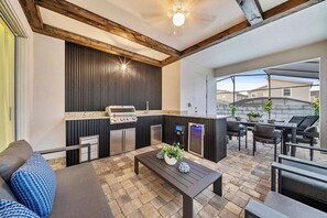 Eine Außenpatio mit Grill, Sitzgelegenheiten und einem Steinboden.