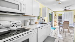 A modern kitchen with white cabinets, a microwave, stove, and coffee maker. - Palm Breeze - 3 Bedroom Mins from Beach (Holmes Beach)