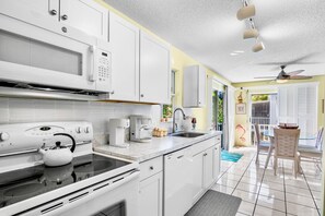 A modern kitchen with white cabinets, a microwave, stove, and coffee maker.