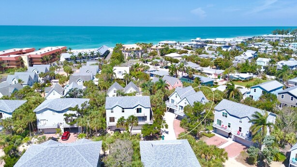 A coastal residential area with houses, some with balconies, and a beach in the background. - Palm Breeze - 3 Bedroom Mins from Beach (Holmes Beach)