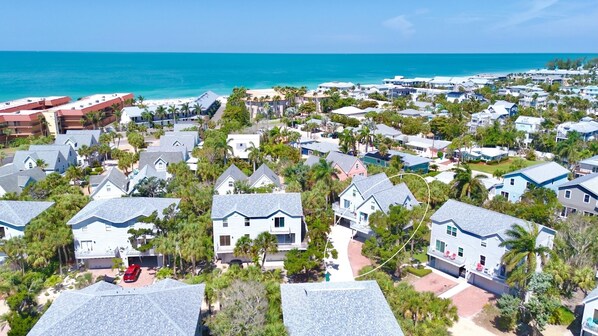 Zona residencial costera con casas, algunas con balcones, y una playa al fondo.