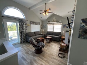 A living room with a sofa, armchair, coffee table, and a ceiling fan. - Ocean Sands 4 Bedroom Private Pool In Culdesac Walk to Beach! The Drift - Woods (COROLLA)