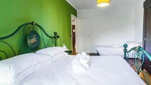 Een hotelkamer met twee bedden, een groene wand en een geel lamp.