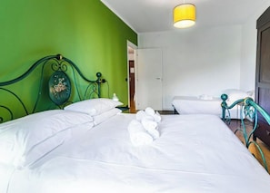 A hotel room with two beds, a green wall, and a yellow light fixture. - PoloTuristicoUmbria Apt Sicilia (Perugia)