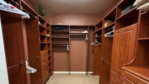 Un vestidor con estantes de madera, cajones y espacio para colgar.