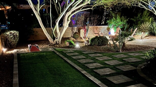 Un jardín cuidado con un sendero empedrado, una piscina pequeña y una mesa decorada con banderas estadounidenses.