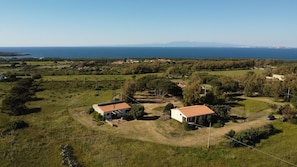 Ein ländliches Anwesen mit zwei Häusern, freiem Blick auf das Meer und einer hügeligen Landschaft.