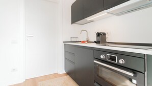 Une cuisine moderne avec des meubles de couleur sombre, un plan de travail blanc, un four encastré et un robinet en acier inoxydable.
