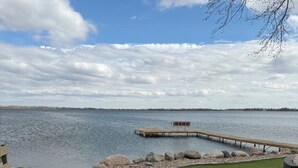 Une zone herbeuse avec une jetée en bois qui s’avance sur une étendue d’eau.