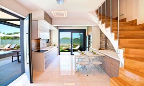 Eine moderne Küche mit Essbereich, einer Treppe und Blick auf die Terrasse.