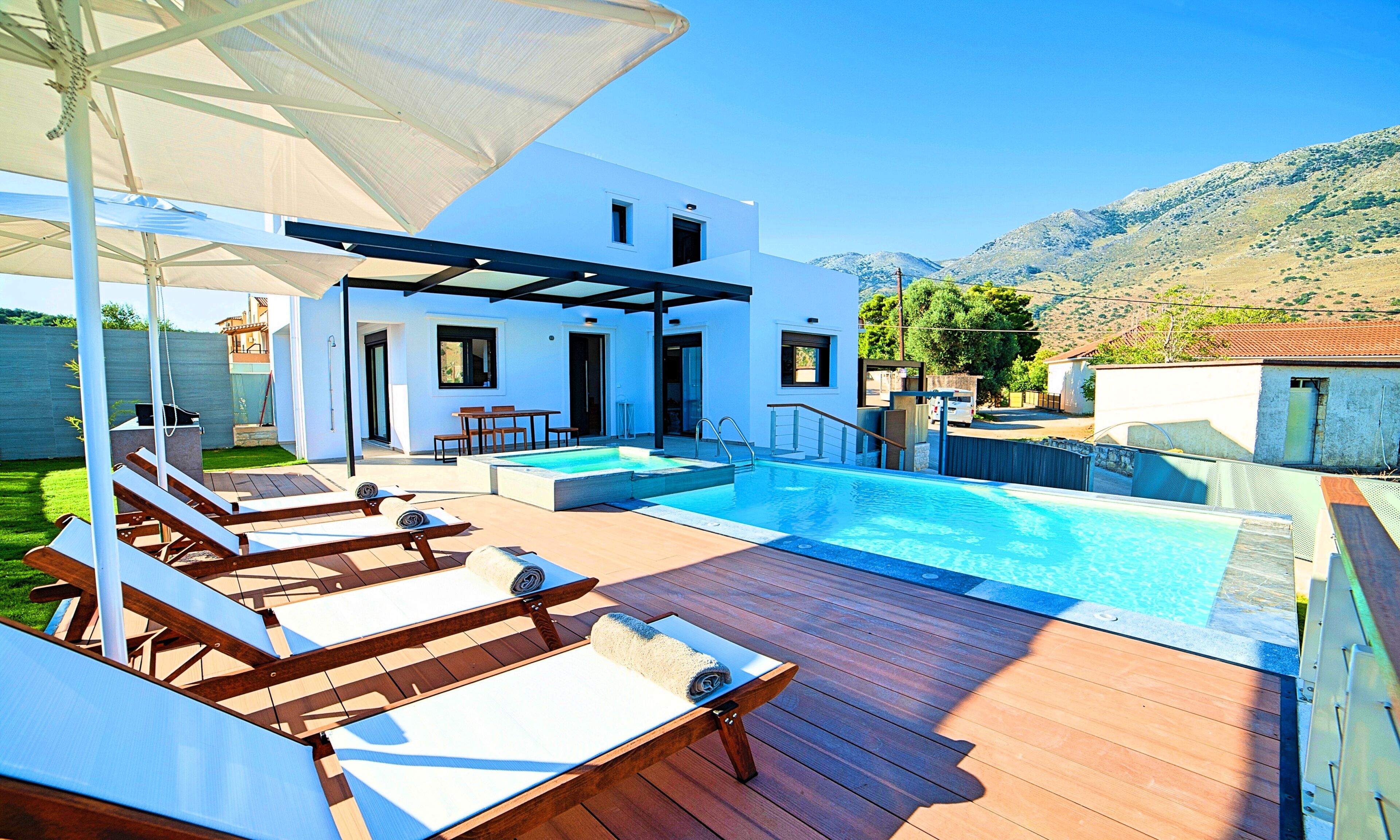 Una piscina con lettini e ombrelloni, un portico coperto e vista sulle colline.