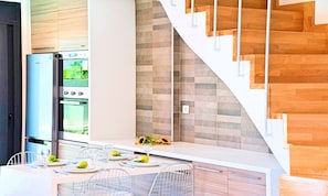Eine moderne Küche mit Einbauofen, einem Edelstahl-Kühlschrank und einer Holztreppe.