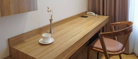 A modern room with a wooden desk, a chair, a vase with dried plants, and a telephone.