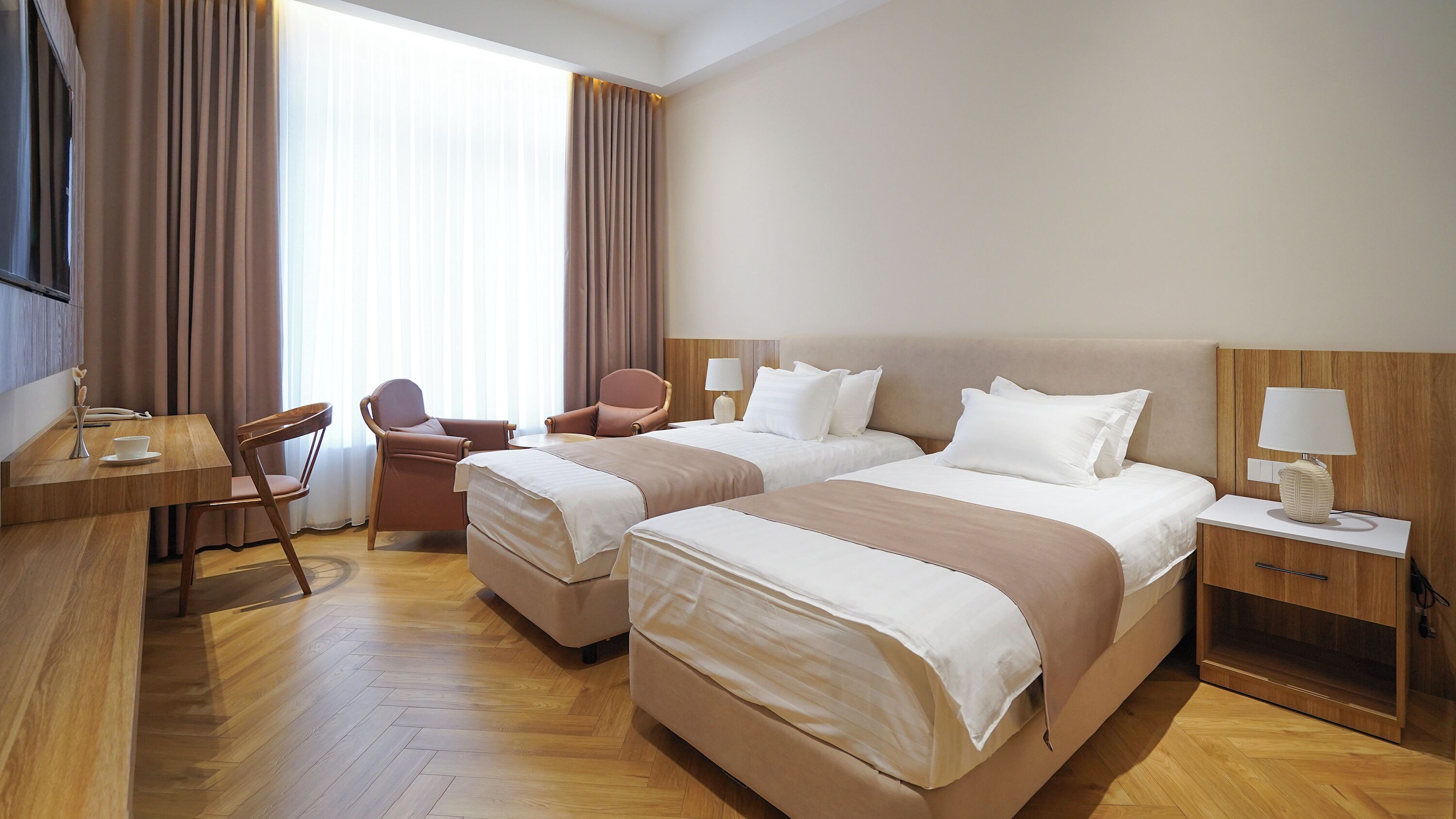 Une chambre d’hôtel avec deux lits, un bureau, une chaise, une lampe et un téléviseur.