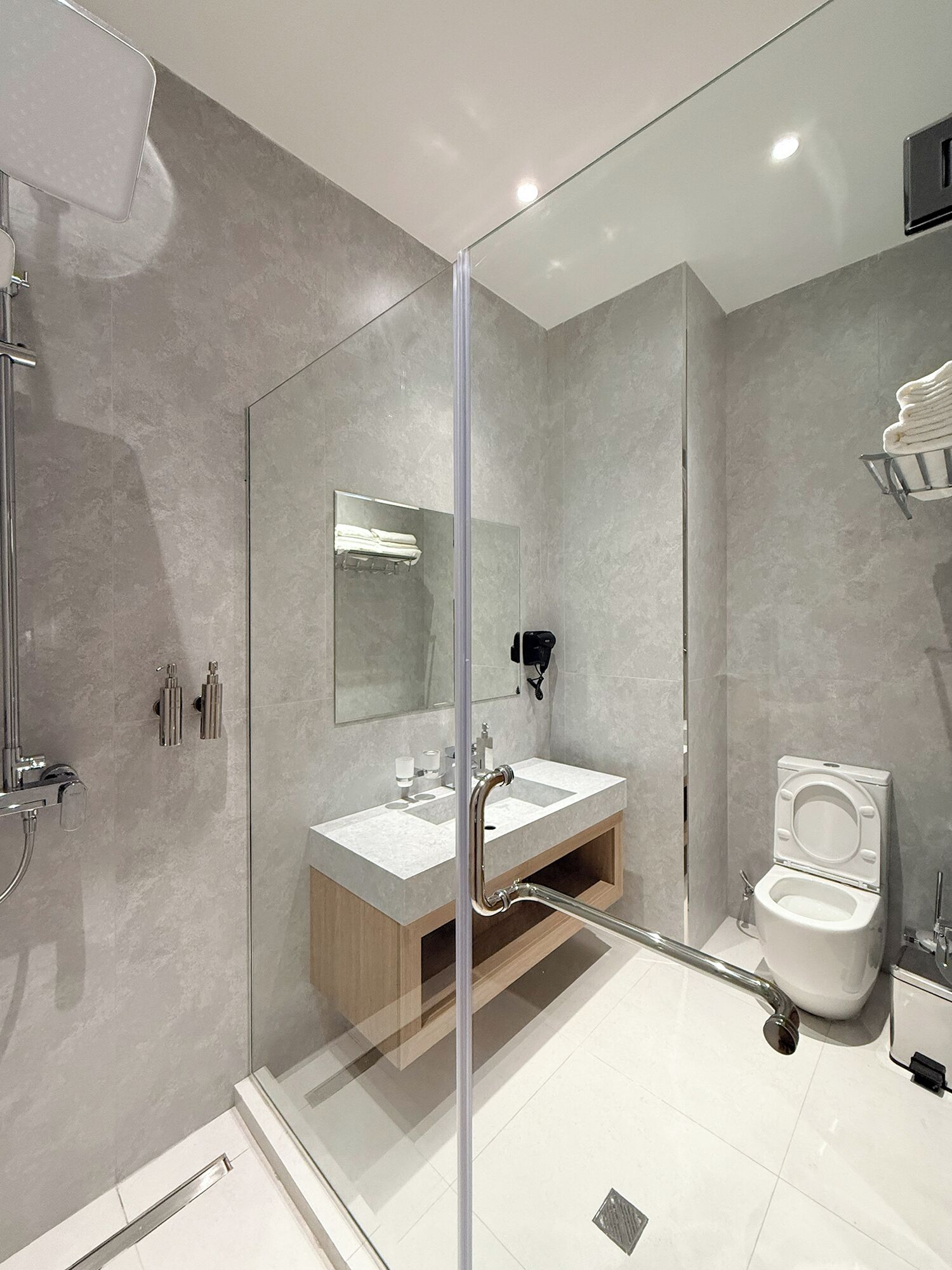 A modern bathroom with a glass shower enclosure, a sink with a mirror, and a toilet.