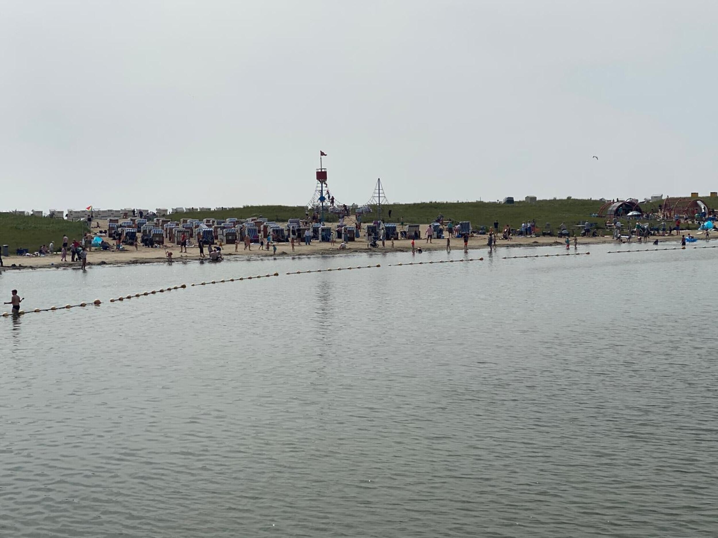 A beach with people, tents, and a tower structure.