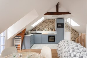 A compact kitchen with a stone backsplash, a microwave, and a sink. - La Petite Maison Bleue - À 400 m de la plage (Dinard)