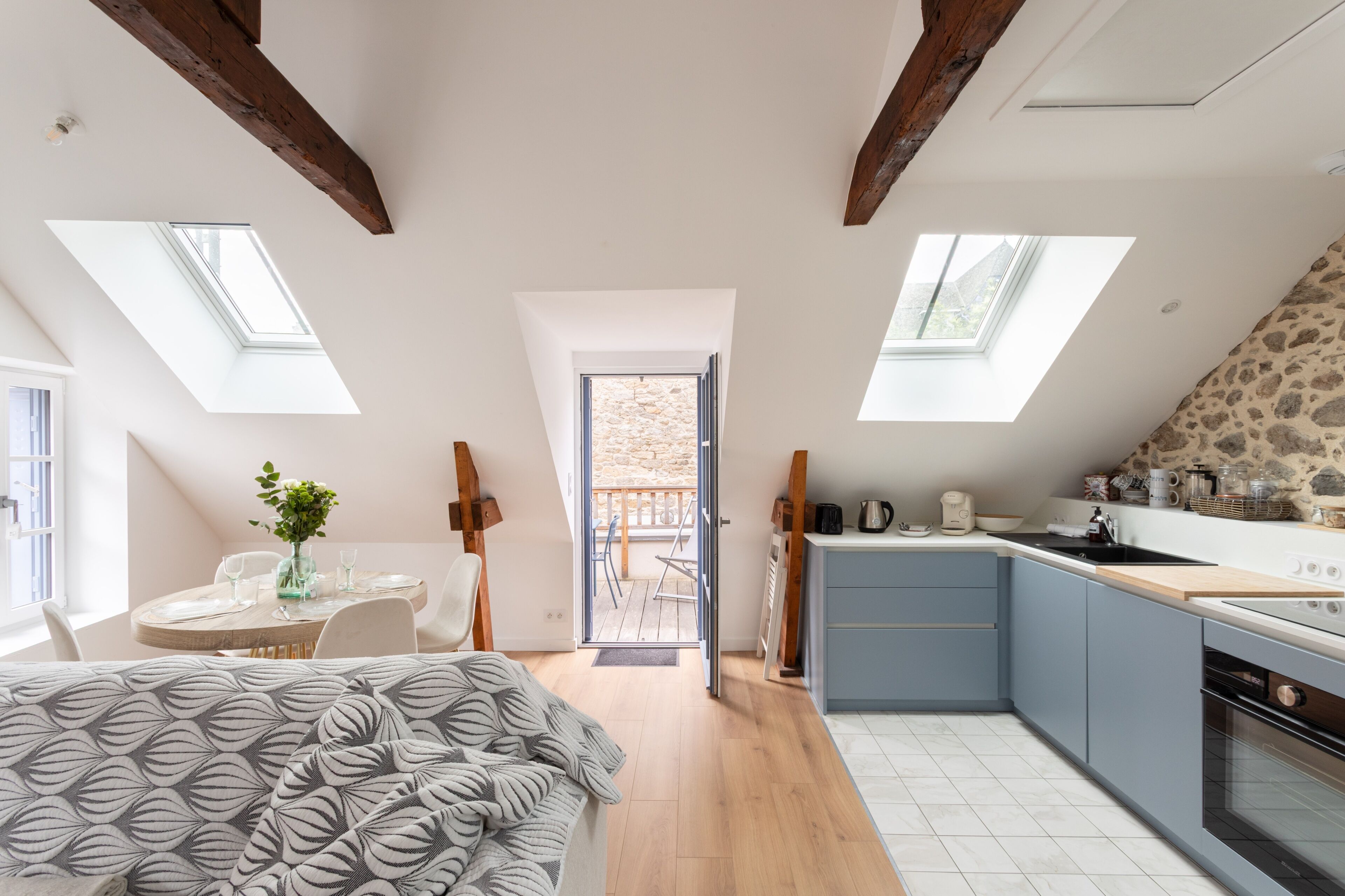Une cuisine moderne dotée de fenêtres de toit, un coin repas et une chambre à coucher avec une couvre-lit à motifs.