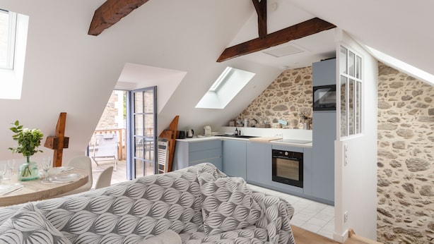 Um quarto estilo loft com cozinha, área de refeições e uma janela grande.