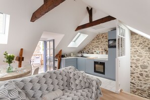 A loft-style room with a kitchen, a dining area, and a large window. - La Petite Maison Bleue - À 400 m de la plage (Dinard)